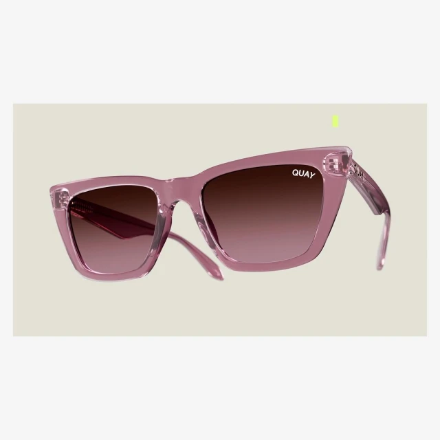 Pink Quay sunglasses with brown gradient lenses isolated against a light gray backdrop in a product-style studio shot.