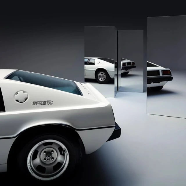 Rear view of a classic white Lotus Esprit car in a photo studio with mirror props reflecting multiple angles of the vehicle.