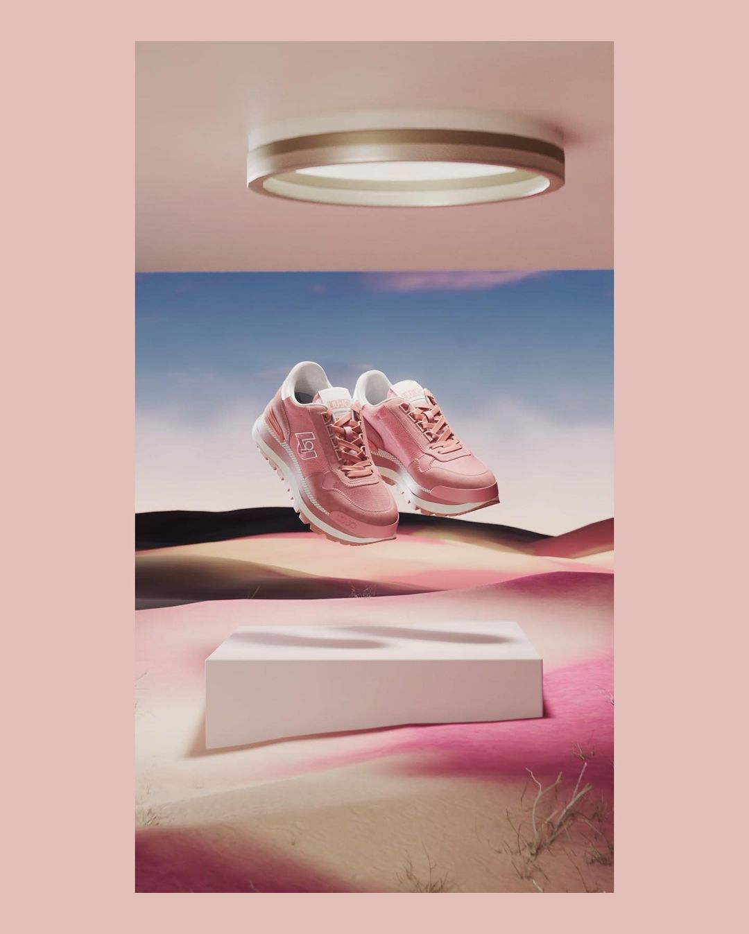 Elevated shot of pink sneakers on a white platform against a backdrop of desert and sky, illuminated by a round ceiling light.