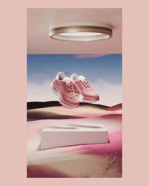 Elevated shot of pink sneakers on a white platform against a backdrop of desert and sky, illuminated by a round ceiling light.