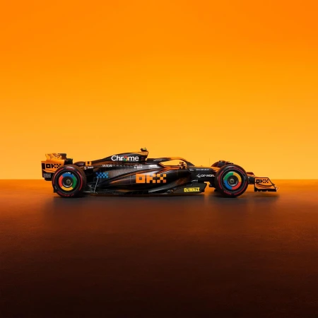 McLaren Formula 1 race car in black and orange with Google Chrome themed wheels, set against a gradient orange backdrop.