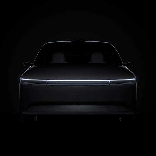 Front view of a dark luxury electric car in deep shadow with a horizontal illuminated light bar across the front grille.