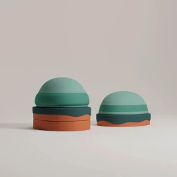 Two rounded sculptural objects with green domed tops and orange bases against a neutral studio background