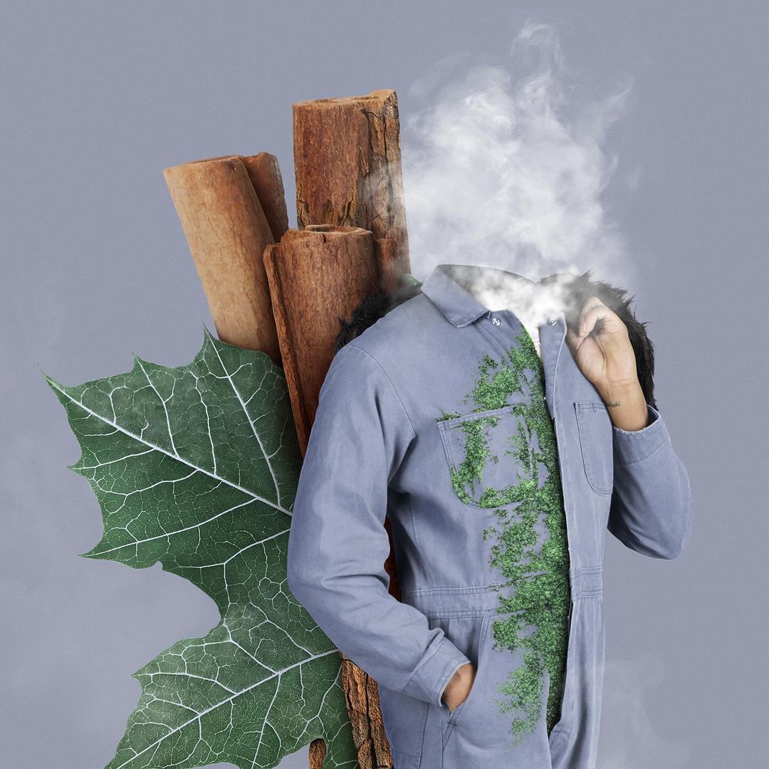 Surreal fashion portrait of a person with smoke obscuring their head, wearing an overall, next to a leaf and wooden logs.