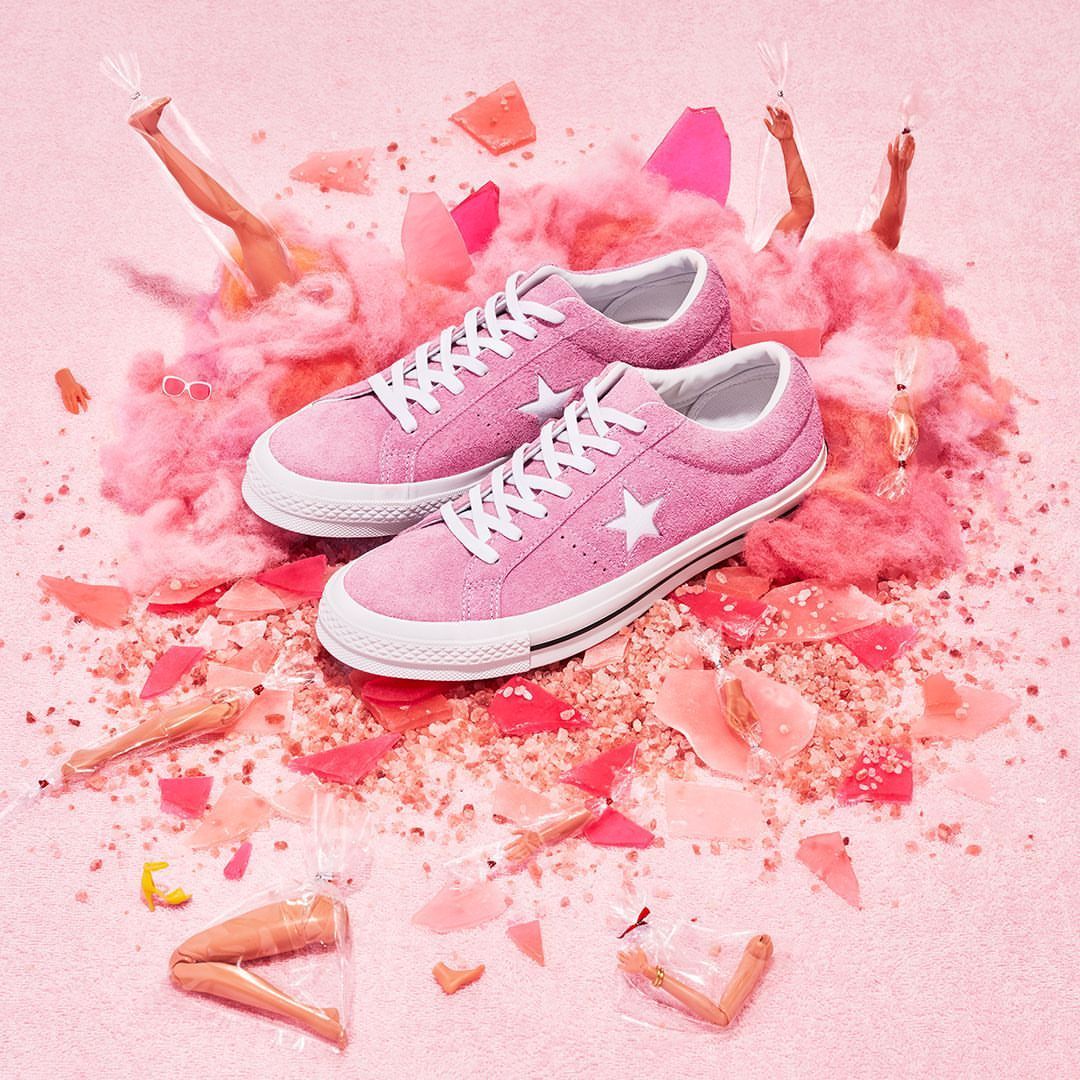 Pink One Star Converse sneakers on pink background with white laces, surrounded by pink cotton candy and deconstructed fashion doll parts.