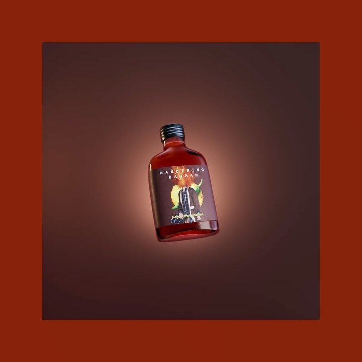 A close-up studio shot of a red liquid in a small glass bottle with a black cap, showcasing its label against a warm brown backdrop.