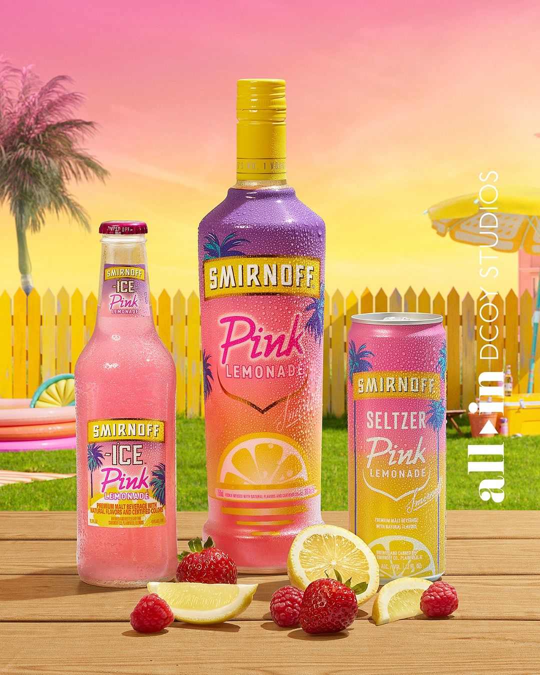 Smirnoff Pink Lemonade beverages including a bottle, can, and ice drink are arranged with strawberries and lemons on a wood surface.