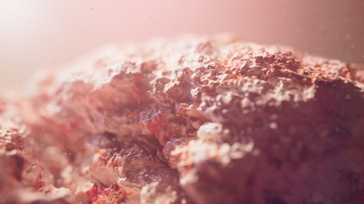 Close-up of rough rock or stone formation with textured surface and pinkish hue, illuminated by soft light, creating an abstract landscape.
