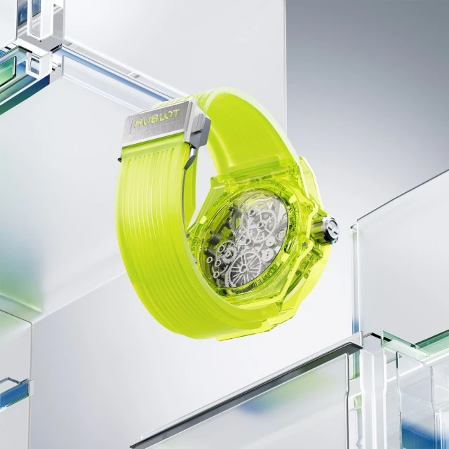 Close-up studio shot of a Hublot watch with a transparent case and neon yellow band, showcasing its internal mechanics and modern design.