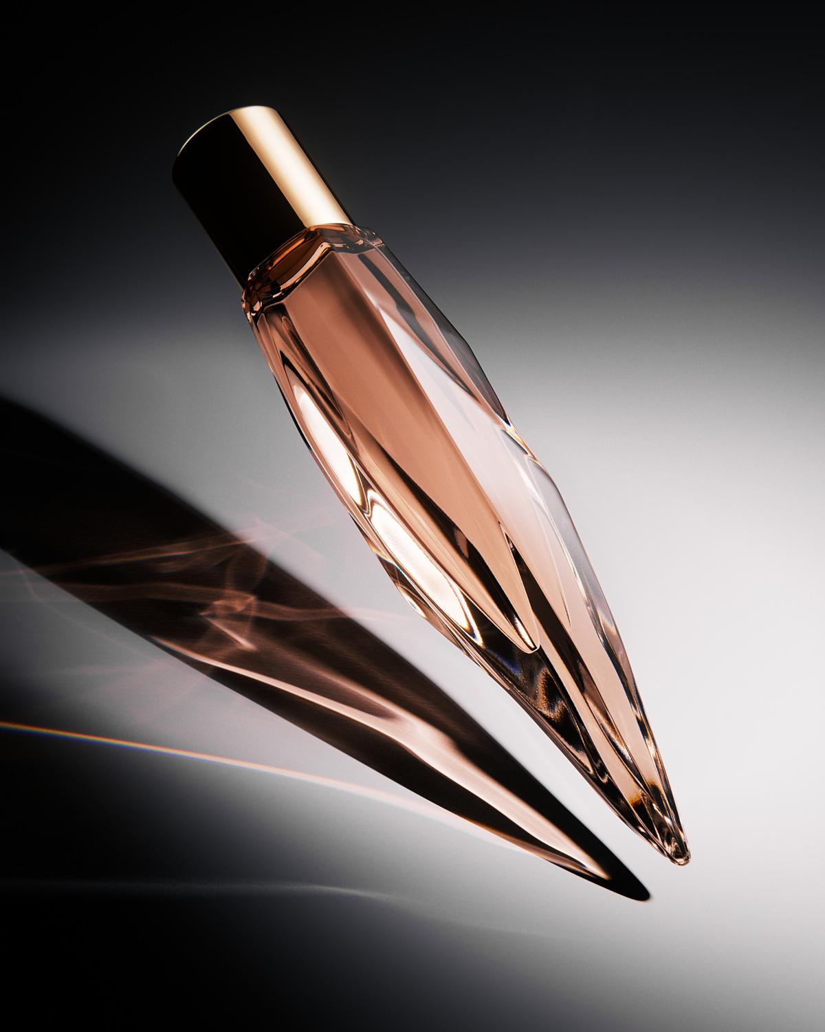 A sleek, angular perfume bottle with a gold cap stands on a surface with its dark shadow, creating a minimalist and elegant composition.