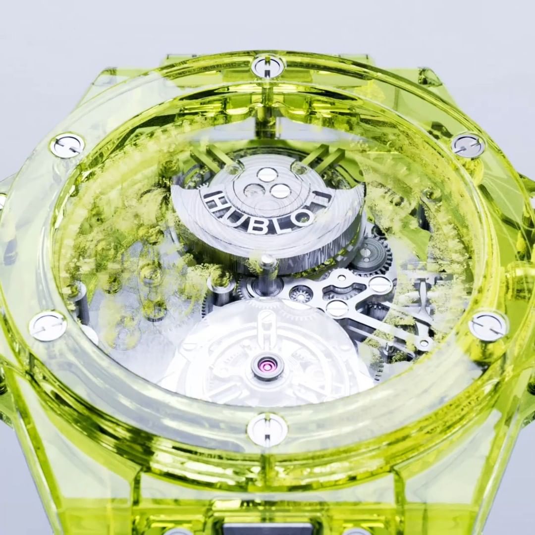Close-up of a transparent yellow Hublot watch showcasing its intricate internal mechanisms against a clean, bright background.