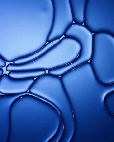 Abstract close-up of connecting blue fluid shapes and forms creates a bubbly effect, featuring smooth gradient transitions.