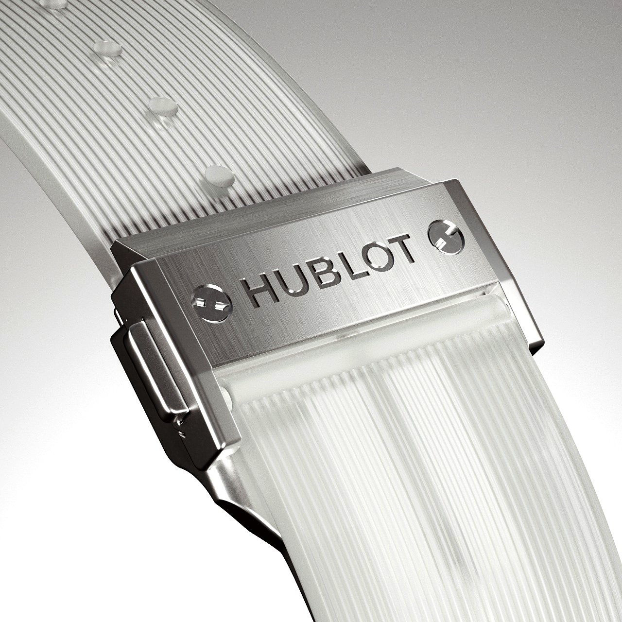 Close-up of a Hublot watch buckle and clear band showing the brand name against a neutral gradient background in a studio shot.