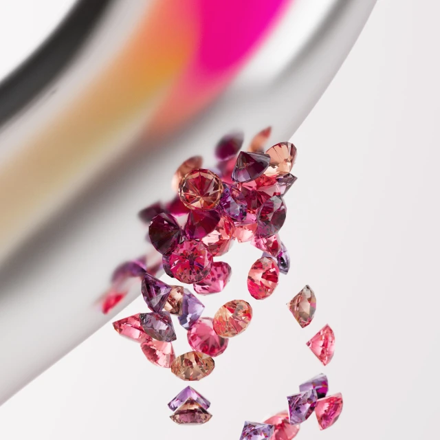 Scattered pile of pink, orange, and purple gemstones refracting light, with blurred abstract pink, white, and orange background gradients.