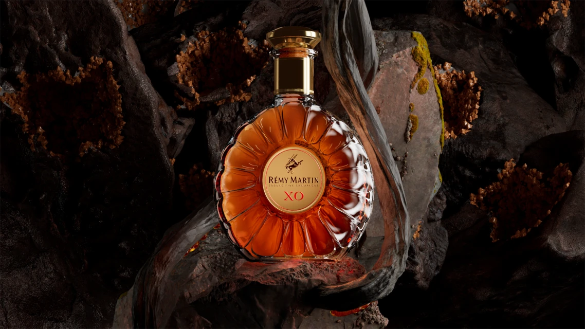 Bottle of Remy Martin XO cognac on a dark, textured surface. Luxury beverage advertising with a focus on bottle design and product presentation.