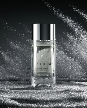 Issey Miyake Le Sel d Issey perfume bottle centered against a dramatic splashing water and crystalline spray backdrop