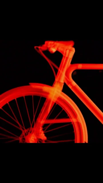 Striking neon red bicycle frame and wheels on a contrasting black backdrop, creating a vibrant and dynamic minimalist image.