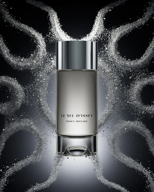 Bottle of Le Sel d'Issey Issey Miyake perfume with a gray-silver bottle and cap, surrounded by white powder against a dark background.