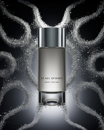 Bottle of Le Sel d'Issey Issey Miyake perfume with a gray-silver bottle and cap, surrounded by white powder against a dark background.