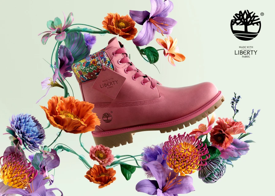 Pink Timberland boot surrounded by an arrangement of vibrant flowers in orange, purple, and green against a light green background.