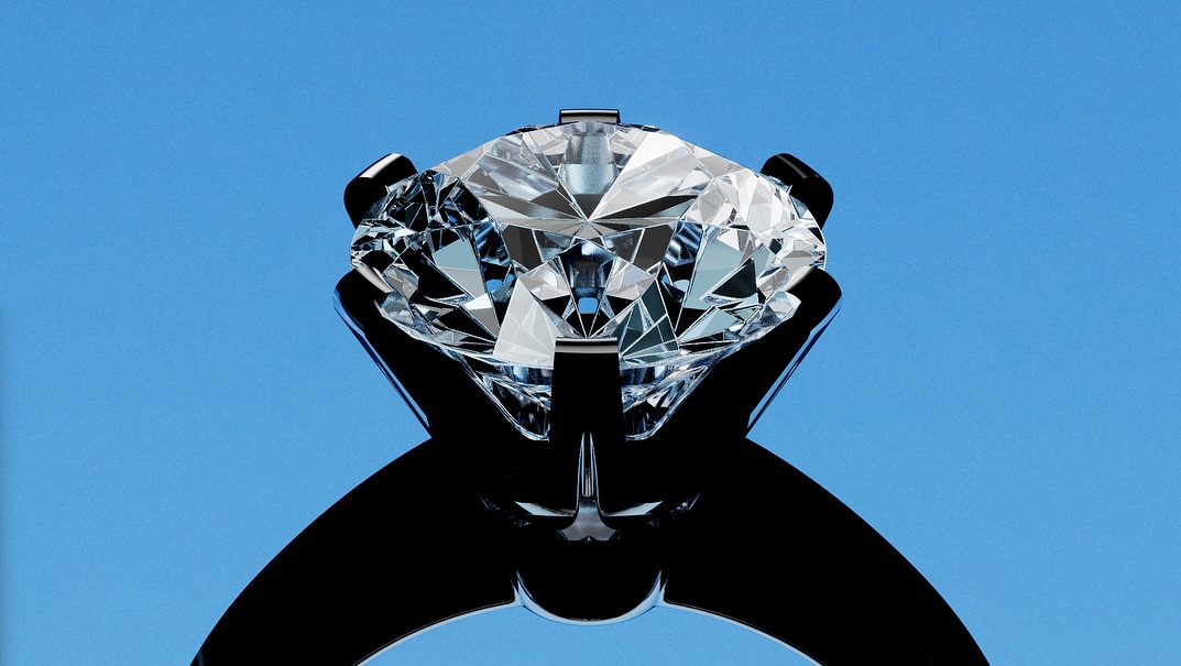Close-up studio shot of a black ring featuring a large, clear diamond against a vibrant blue background, showcasing jewelry design.