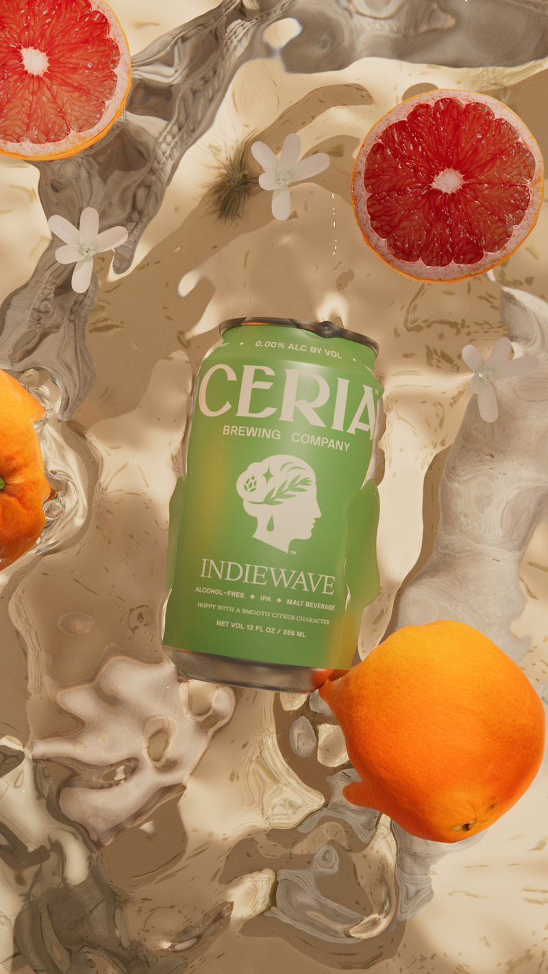 Craft beverage advertisement featuring a pale green can of Cería IndieWave beer surrounded by orange and grapefruit slices in water.