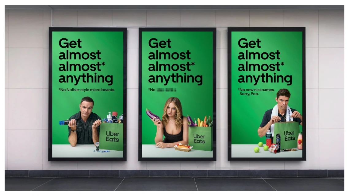 Three posters advertise Uber Eats with images of adults and food. The ads are displayed on a textured wall.