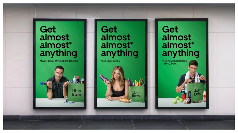 Three posters advertise Uber Eats with images of adults and food. The ads are displayed on a textured wall.