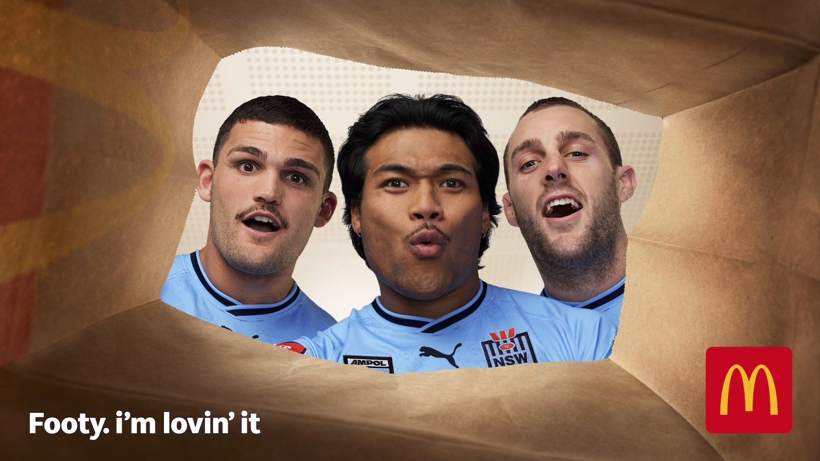 Three adult male athletes in sports jerseys are seen from inside a brown paper bag in a promotional image for fast food.
