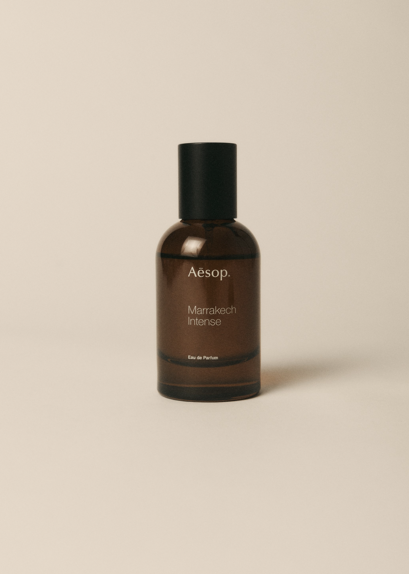 Close-up studio shot of an Aesop Marrakech Intense perfume bottle with a brown bottle and black cap, set against a neutral background.