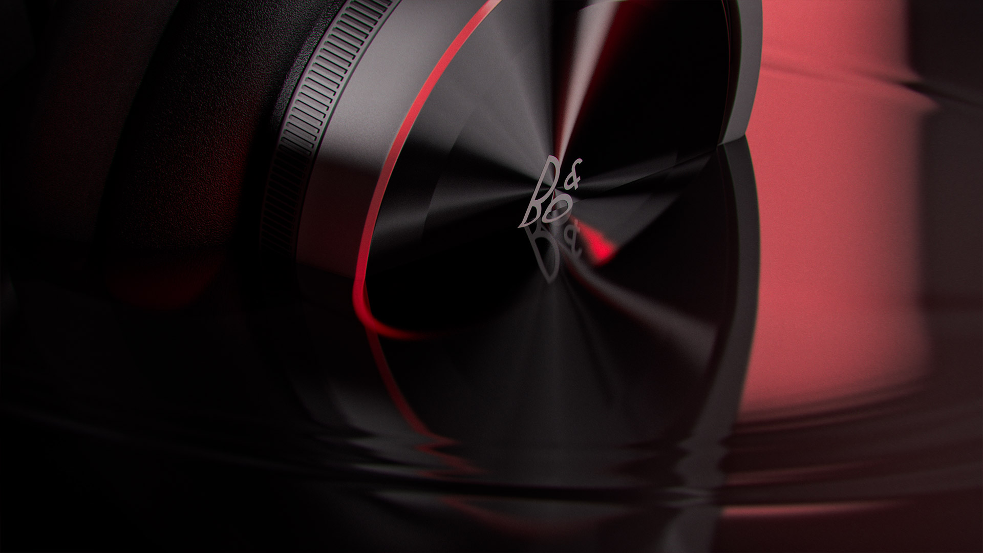 Sleek black and silver speaker with the B&O logo prominently displayed against a soft red background, reflected in rippling water.