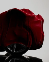 Red fabric draped over a vehicle with a visible alloy wheel against a clean grey background by Joy Cgi