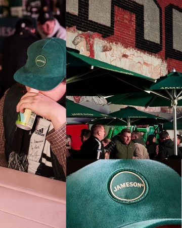 Patrons socializing outdoors under green Jameson umbrellas; one person drinks from a can and wears a branded cap.