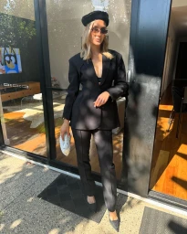 Woman wearing a black suit and beret holding a white clutch standing in a doorway