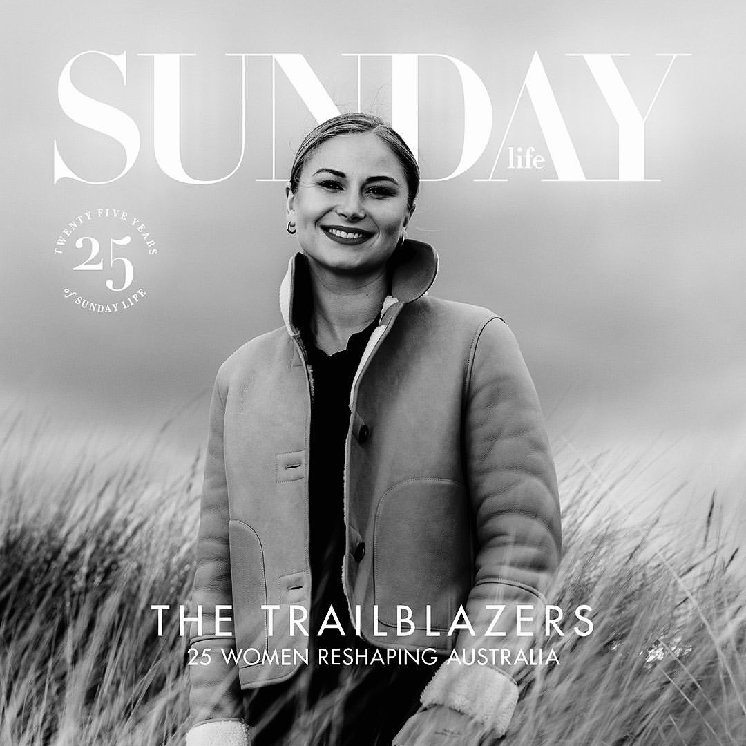 Sunday Life magazine cover featuring a smiling woman in a shearling coat standing in tall grass with a cloudy sky backdrop.