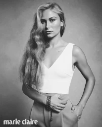 Portrait of Grace Tame in a white sleeveless crop top against a textured grey background
