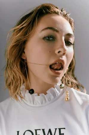 Close up portrait of a woman with wet blonde hair wearing drop earrings and a white t-shirt styled by Sophie Barker