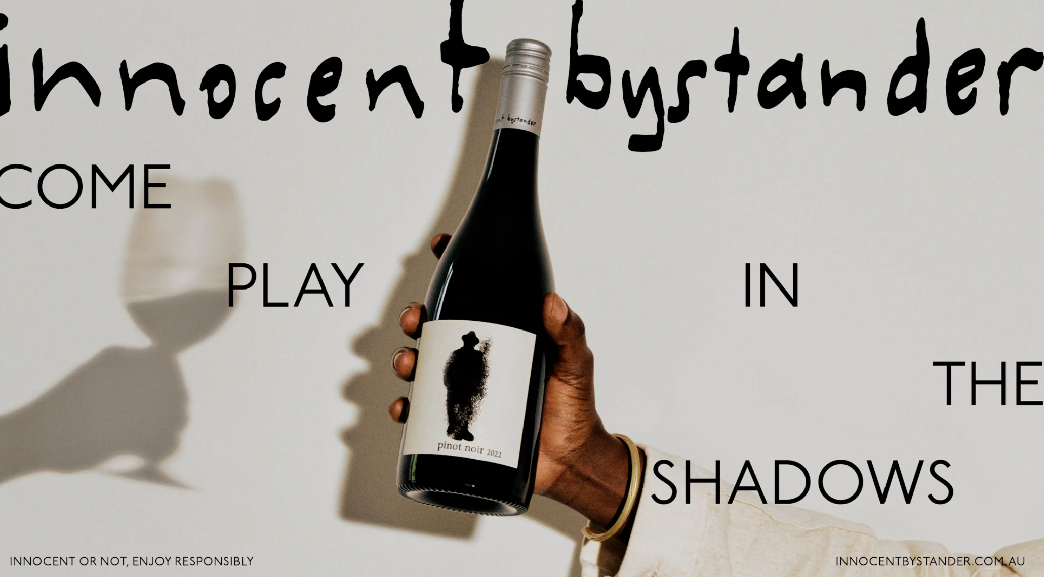 Wine bottle held by a hand, showcasing a minimalistic label with the text 'pinot noir 2022'. The composition is clean and modern.