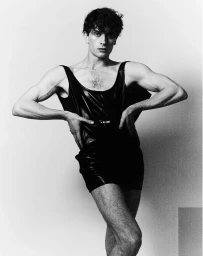 Man in black leather tank top posing against a plain background