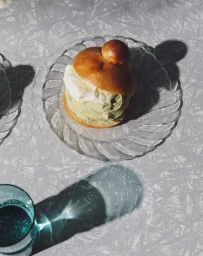 Brioche bun filled with green pistachio ice cream and white cream on a glass plate styled by Deborah Kaloper