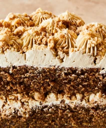 Close-up macro shot of a spiced layer cake with crumb topping and piped cream frosting, styled by Lee Blaylock.