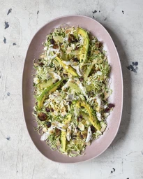 Avocado and shaved Brussels sprout salad styled on an oval pink ceramic platter