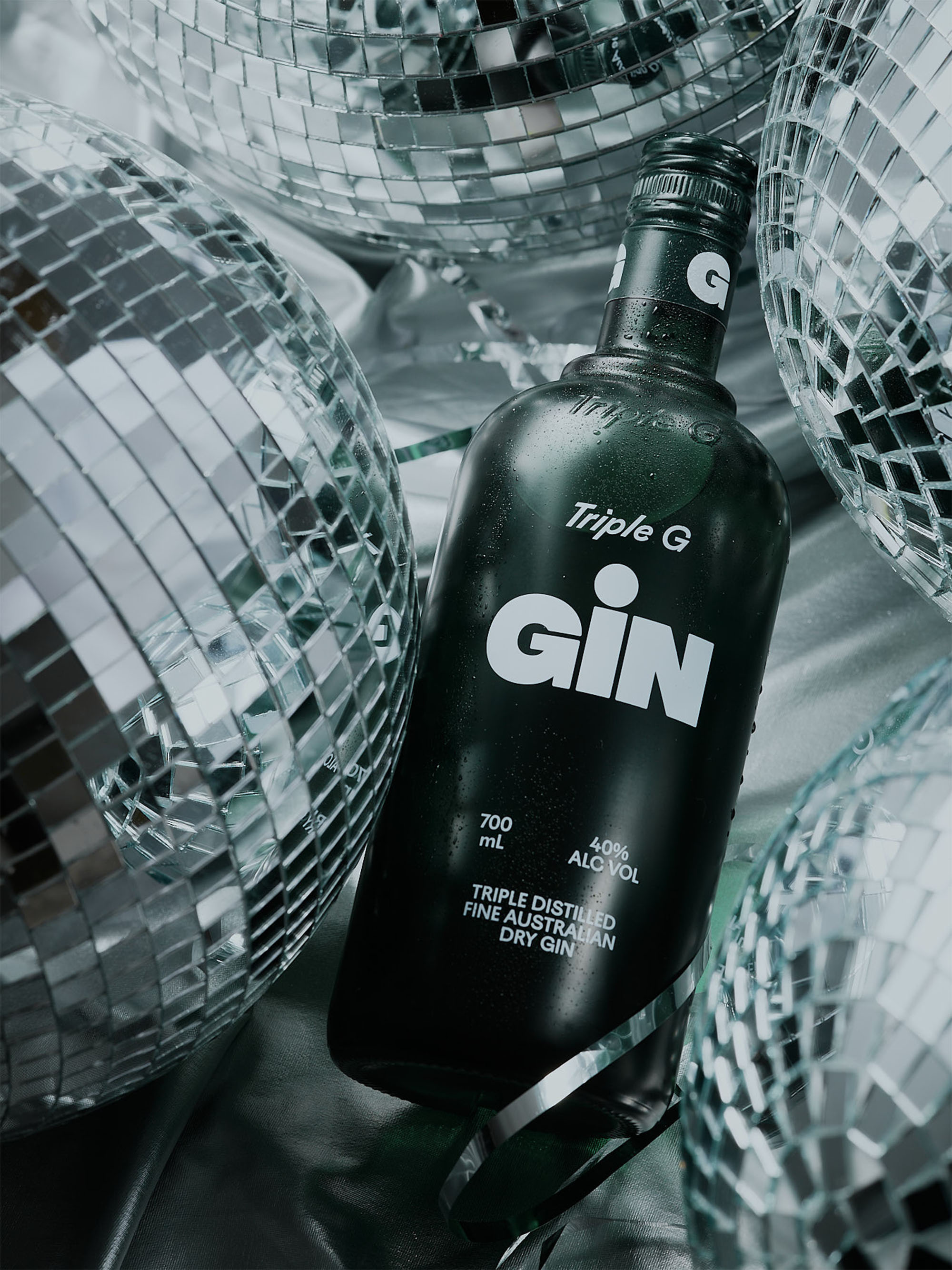 Close-up of a dark green gin bottle with disco balls, showcasing reflective surfaces and product details for beverage advertising.