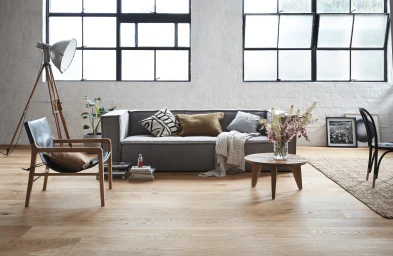 Contemporary living room interior styled by Rachel Vigor featuring a grey sofa, wooden coffee table, and large multi-pane windows.
