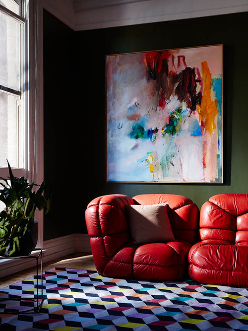 Interior design featuring a red leather modular sofa, a colorful geometric rug, a modern art piece, and a green potted plant.