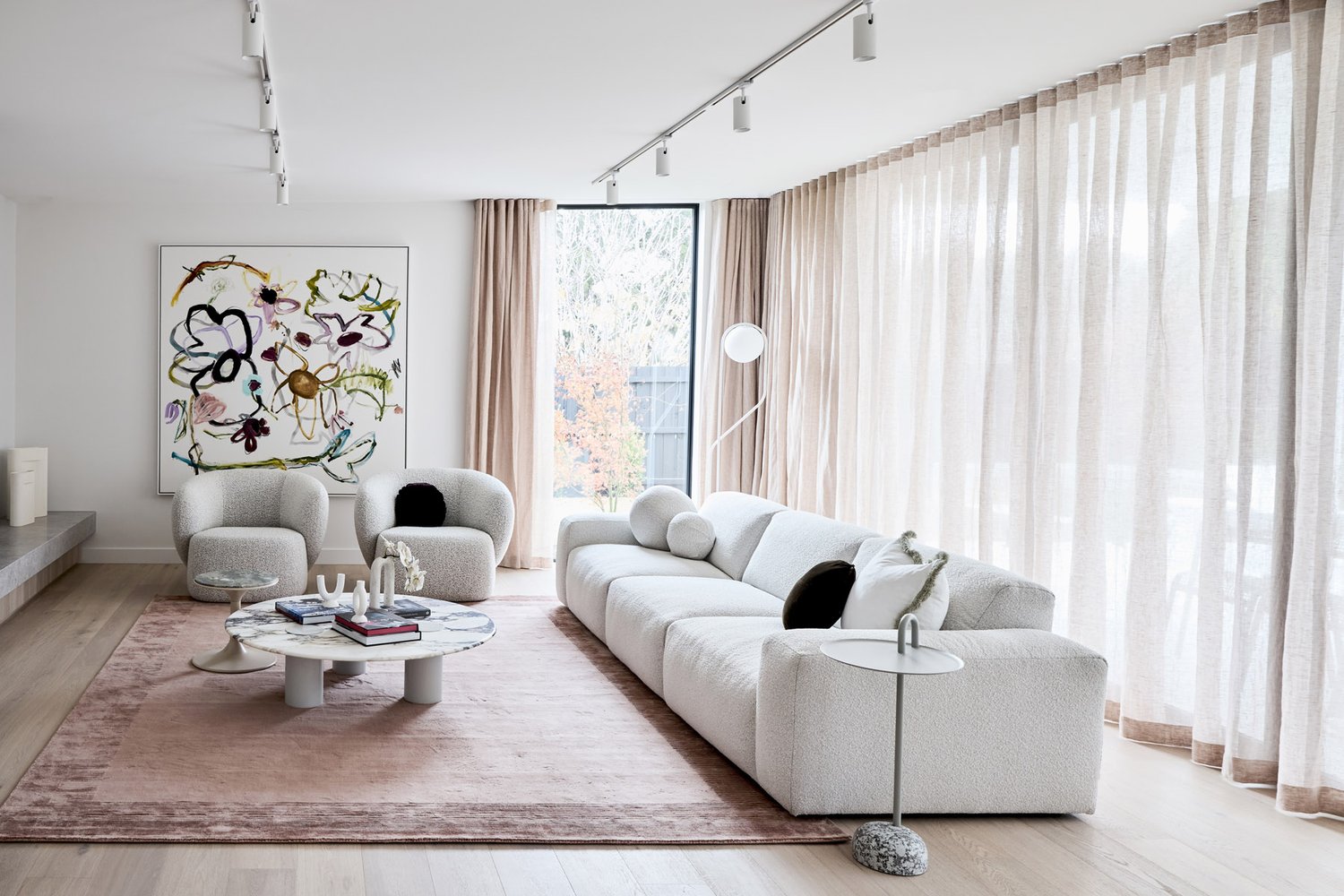 Contemporary living room interior showcasing a textured white sofa, round marble coffee table, and abstract art on a white wall.