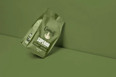 Green coffee bag resting against an olive green studio backdrop, photographed by Daniel Hermann Zoll
