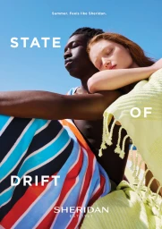 Close-up portrait of a Black man and a red-haired woman leaning together outdoors under a bright blue sky.