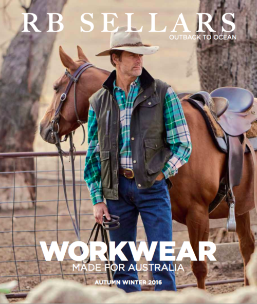 A male rancher in workwear stands next to a brown horse outdoors. He wears a cowboy hat, vest, and jeans, in a rural setting with trees.