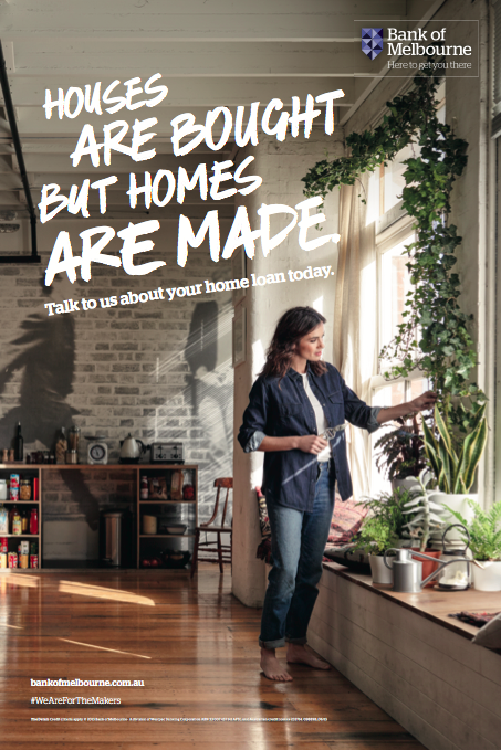 Woman stands near a window with many houseplants in an apartment with natural lighting, brick walls, and wood floors; home loan ad.